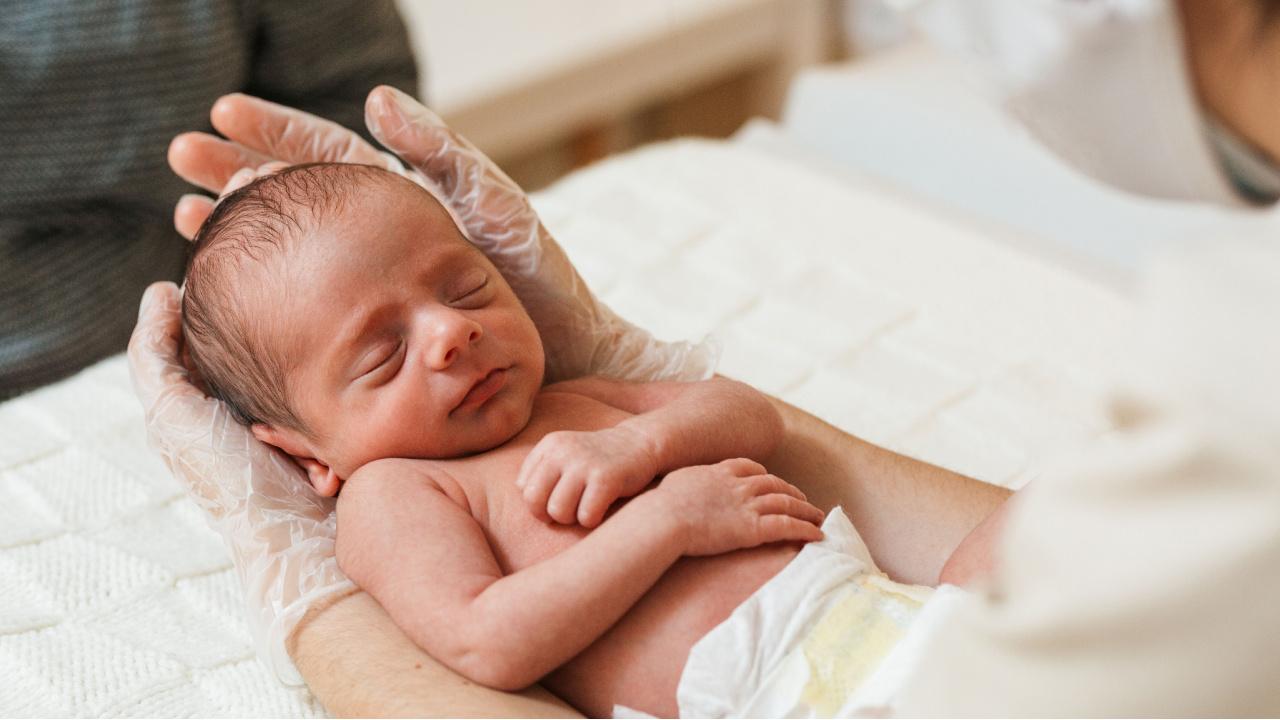 Naujagimį apžiūri gydytojas, naujagimio krūtų padidėjimas