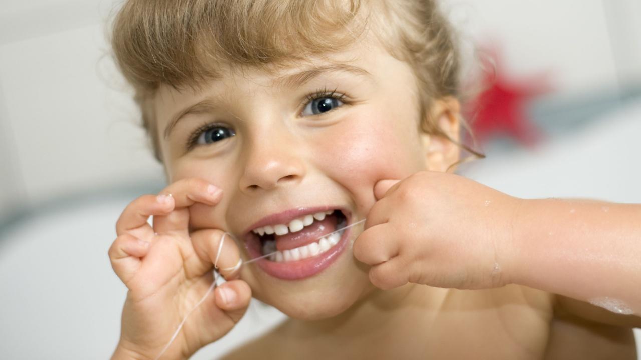 Mergaitė valosi dantis su tarpdančių siūlu