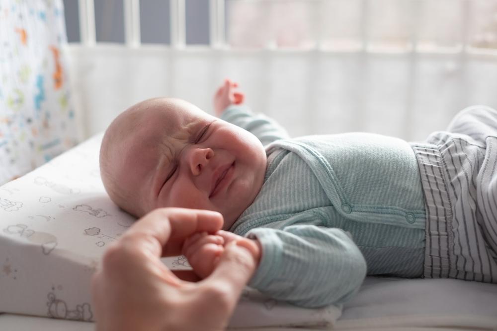 Mama laiko verkiančio kūdikio rankytę