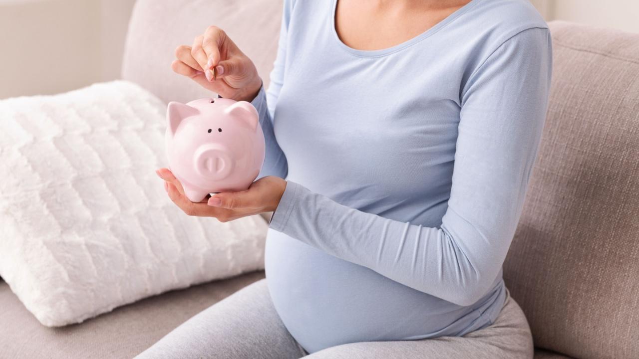 Nėščia moteris deda pinigus į kiaulę taupyklę