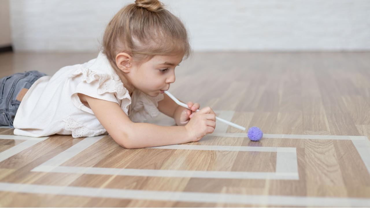 Mergaitė žaidžia žaidimą su šiaudeliu